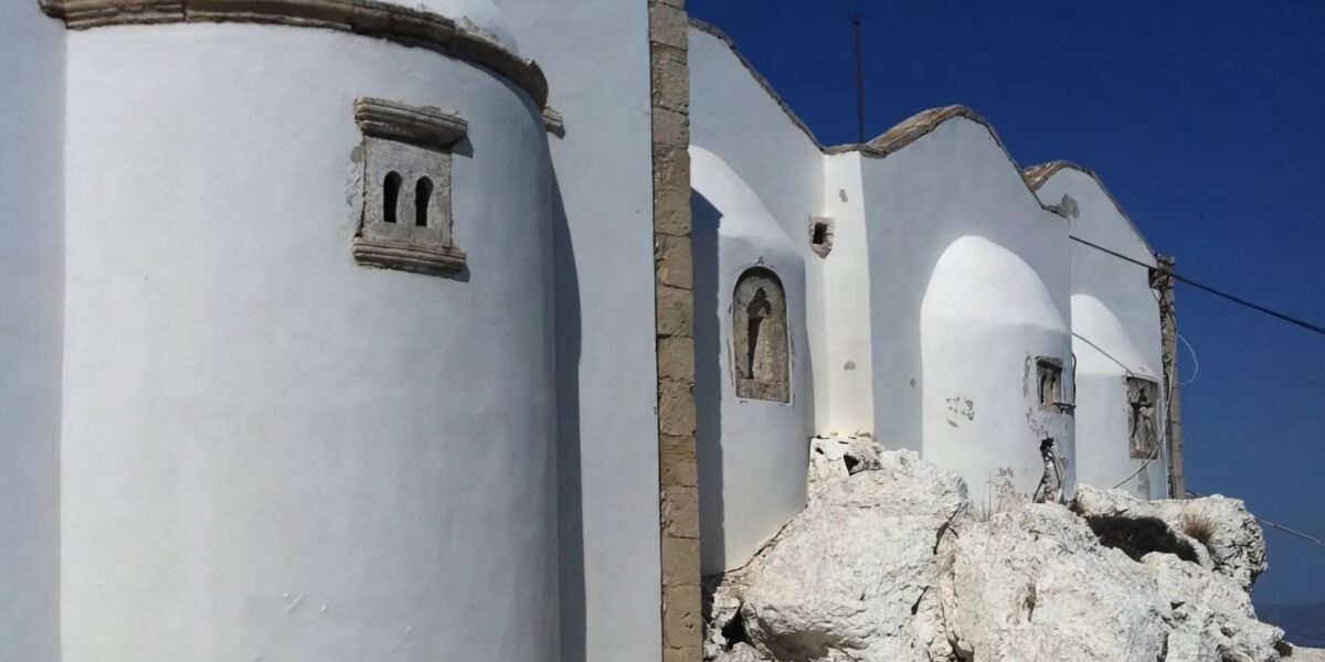 A white building with curved walls and small windows at Juktas Peak Sanctuary.