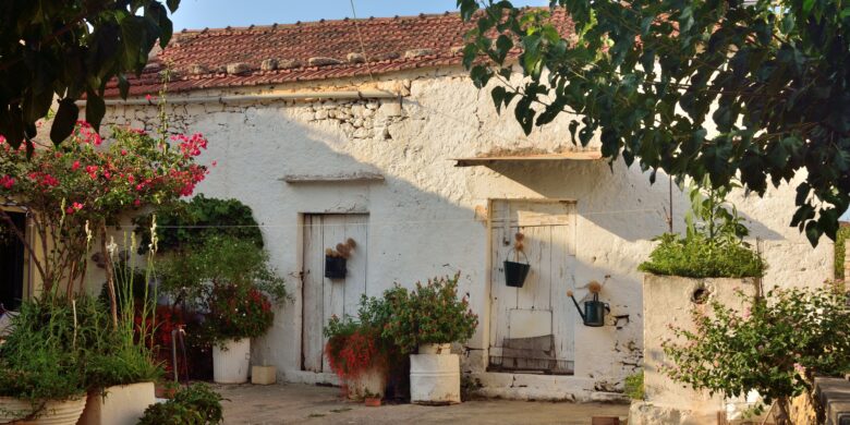 A peaceful courtyard in Vamos village, Crete, featuring whitewashed stone walls, potted plants, and vibrant flowers that enhance the rustic charm.